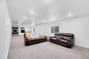 Living room featuring light carpet, visible vents, baseboards, a fireplace, and recessed lighting