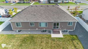 Back of property featuring a fenced backyard, a shingled roof, and a lawn