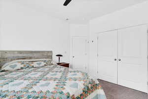 Carpeted bedroom featuring a ceiling fan and a closet