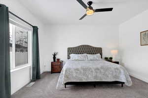 Carpeted bedroom with baseboards, visible vents, and a ceiling fan