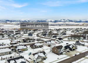 Snowy aerial view featuring a residential view and a mountain view