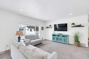 Carpeted living area with recessed lighting, visible vents, and baseboards