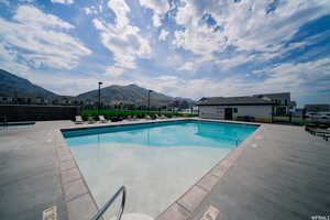 Community pool featuring a patio area, a residential view, fence, and a mountain view