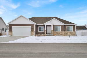 View of front of house featuring an attached garage, fence, stone siding, concrete driveway, and roof with shingles