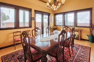 Dining space featuring baseboards, a chandelier, wood finished floors, and french doors