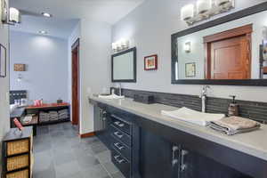 Full bathroom with double vanity, recessed lighting, backsplash, a sink, and baseboards