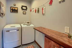 Clothes washing area featuring laundry area, light tile patterned floors, baseboards, and separate washer and dryer