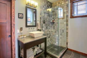 Full bath featuring baseboards, tile patterned floors, a sink, and a shower stall