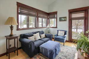 Living room featuring light wood-type flooring, a wealth of natural light, lofted ceiling, and baseboards