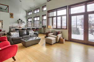 Living room featuring a high ceiling, light wood-style flooring, and baseboards