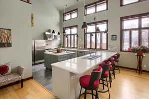 Kitchen with a center island, gray cabinets, light countertops, freestanding refrigerator, and a peninsula