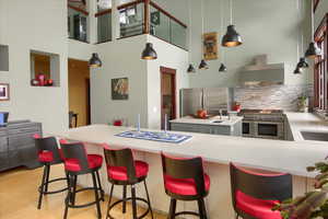 Kitchen with appliances with stainless steel finishes, light countertops, wall chimney range hood, and decorative light fixtures