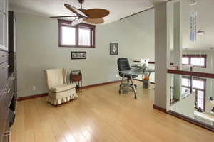 Office with a ceiling fan, plenty of natural light, light wood-style flooring, and a textured ceiling