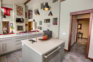 Kitchen featuring a center island with sink, open floor plan, decorative light fixtures, light countertops, and a sink