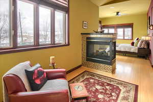 Living area with ceiling fan, a fireplace, baseboards, and wood finished floors