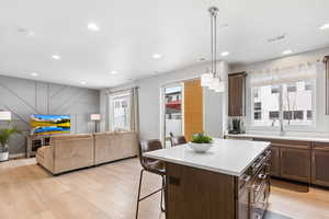 Kitchen featuring a kitchen bar, a kitchen island, light countertops, and open floor plan