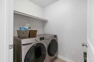 Clothes washing area featuring laundry area, washing machine and dryer, and baseboards