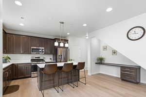 Kitchen featuring appliances with stainless steel finishes, light countertops, hanging light fixtures, and visible vents