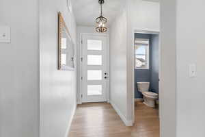 Entrance foyer with an inviting chandelier, light wood-style flooring, and baseboards