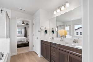 Ensuite bathroom with double vanity, wood finished floors, ensuite bath, and a sink