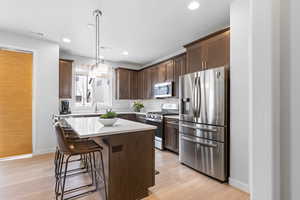 Kitchen with visible vents, a center island, stainless steel appliances, light countertops, and pendant lighting