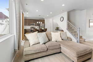 Living area with light wood-type flooring, stairway, visible vents, and recessed lighting