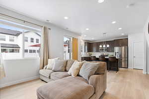 Living area with light wood finished floors, visible vents, baseboards, and recessed lighting