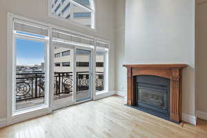 Unfurnished living room with a high ceiling, a fireplace with flush hearth, light wood-style flooring, and baseboards