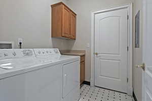 Clothes washing area with washer and dryer, cabinet space, and light floors