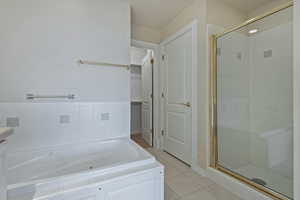 Bathroom featuring a shower stall, a tub with jets, a walk in closet, and tile patterned floors