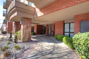 Doorway to property with concrete driveway, brick siding, and visible vents