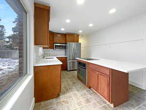 Kitchen featuring a center island, stainless steel appliances, a sink, and light countertops