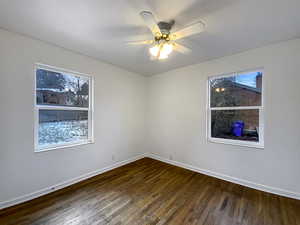 Unfurnished room with a ceiling fan, dark wood-style flooring, and baseboards