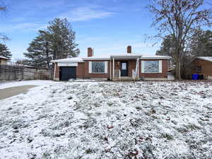 Ranch-style house with a garage, brick siding, a chimney, and fence