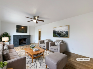 Living room with ceiling fan, a fireplace, baseboards, and wood finished floors