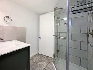 Full bath featuring a stall shower and vanity