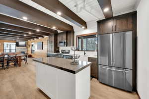 Kitchen featuring stainless steel appliances, light wood-style flooring, a kitchen island, and dark brown cabinetry