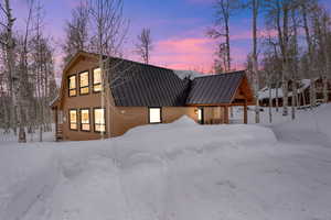 View of front of property with a garage, a standing seam roof, metal roof, and a gambrel roof