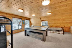 Bedroom featuring wood ceiling, light carpet, and wooden walls