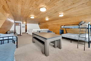 Bedroom with wood ceiling, light carpet, and wooden walls