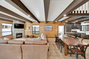 Living room with light wood-type flooring, plenty of natural light, a fireplace, and beamed ceiling