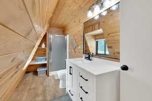 Bathroom featuring wood finished floors, wood walls, a shower stall, and wood ceiling