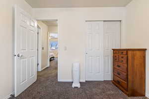 Bedroom with dark colored carpet and a closet