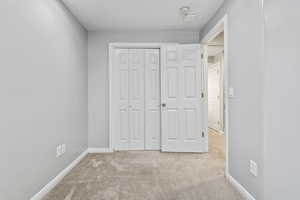 bedroom with light carpet and a closet