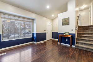 Foyer featuring vaulted ceiling and dark hardwood / wood-style floors  and wainscoting