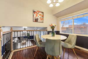 Dining room with a notable chandelier, vaulted ceiling, and hardwood / wood-style floors