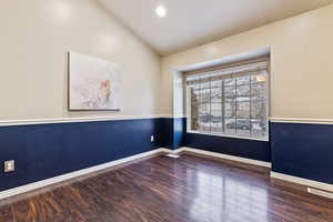 Living room featuring vaulted ceiling and dark hardwood / wood-style floors and wainscoting