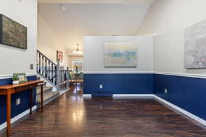 Interior space featuring a notable chandelier, high vaulted ceiling, and dark wood-type flooring  and wainscoting