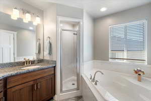 Full bathroom featuring a garden tub, a shower stall, and vanity