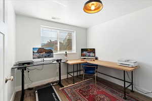 Office space with visible vents, baseboards, and wood finished floors